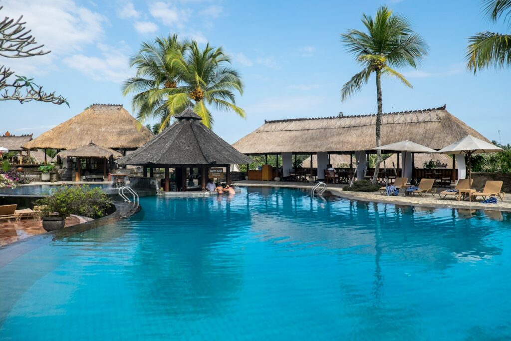 Resort pool with thatched pavilions and palm trees